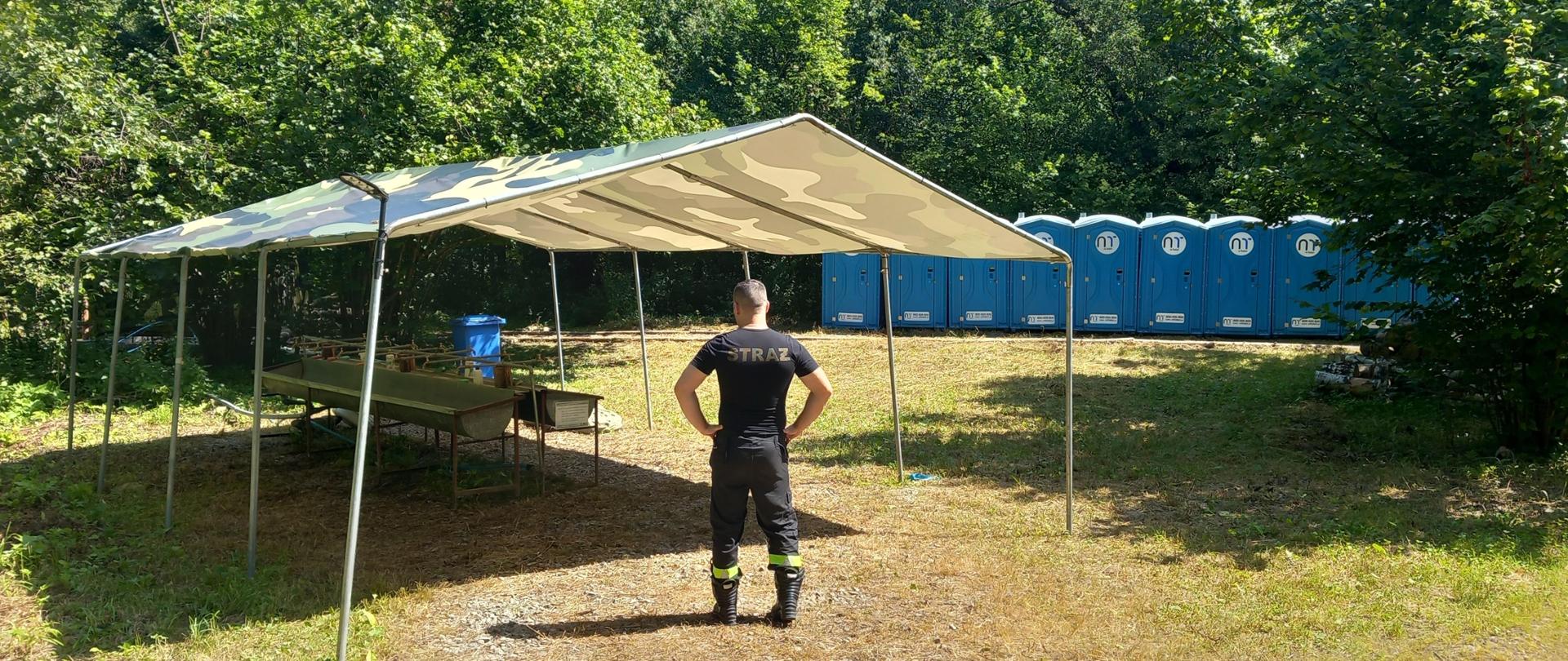 Zdjęcie przedstawia strażaków KP PSP Lesko podczas wizytacji obozu harcerskiego.