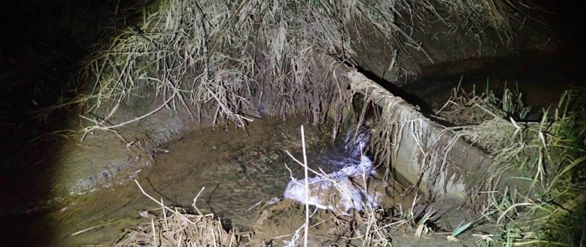 Spieniona i brudna woda wylewa się z uszkodzonego kolektora odprowadzającego ścieki.