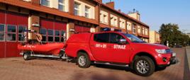 Na zdjęciu zestaw do ratownictwa wodnego, tj. lekki samochód specjalny rozpoznawczo-ratowniczy Mitsubishi L200 oraz łódź ratownicza Whaly zamocowana do przyczepki transportowej. Zdjęcie wykonane na placu manewrowym przed garażami Jednostki Ratowniczo-Gaśniczej.