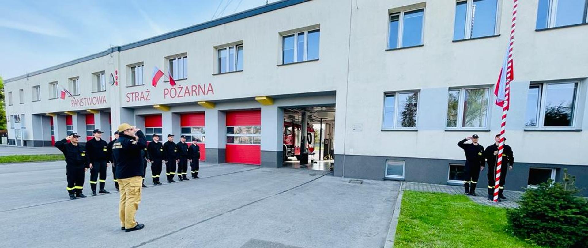 Wywieszanie flagi na maszcie z okazji Dnia Flagi Rzeczpospolitej Polskiej przez funkcjonariuszy KM PSP w Jaworznie przed budynkiem komendy..