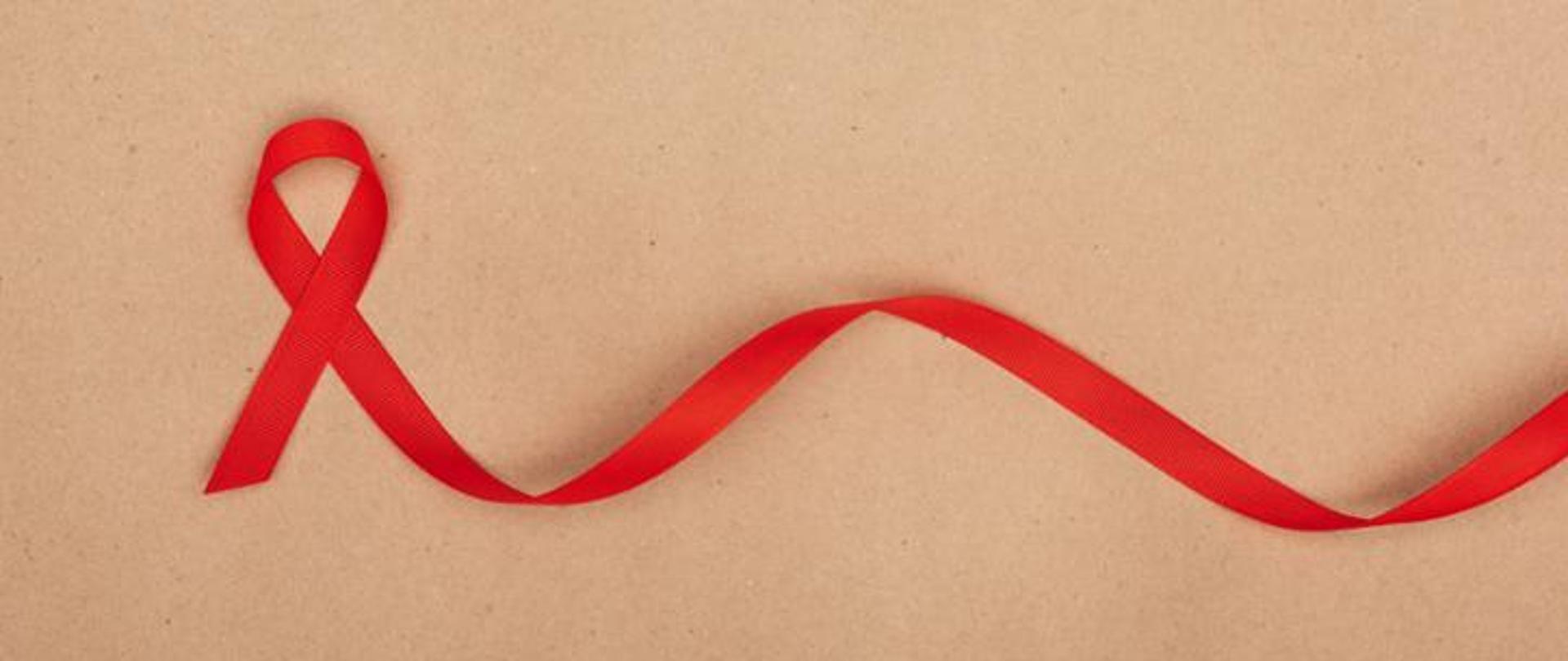 Na beżowym tle czerwona wstążeczka