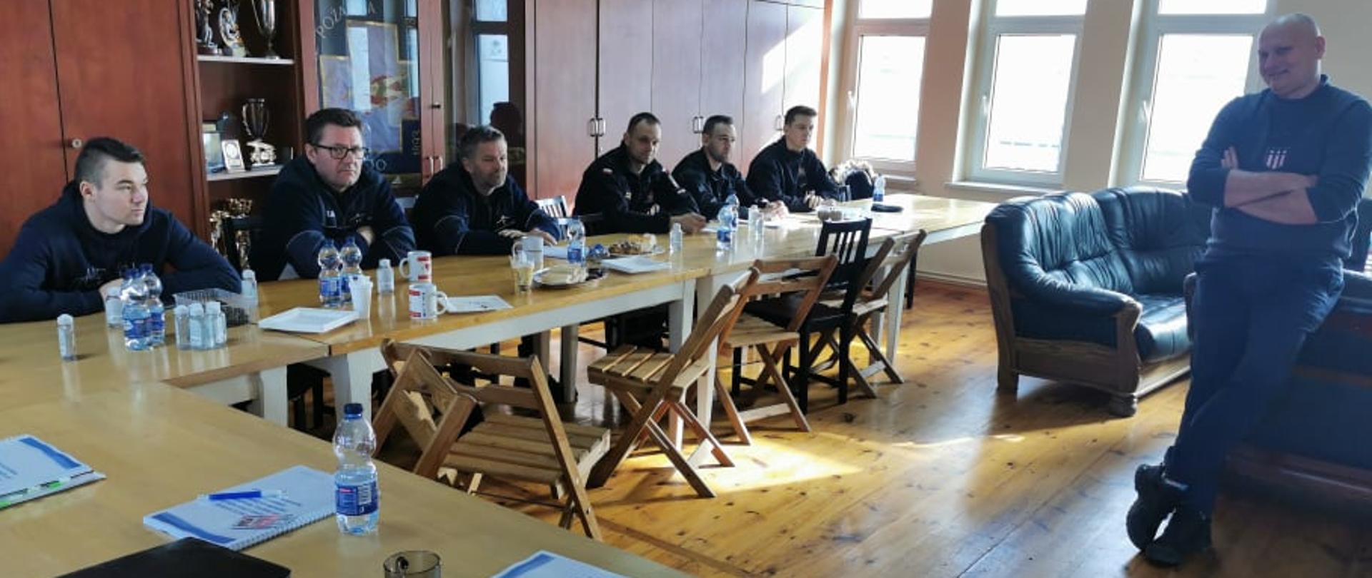 Zdjęcie przedstawia grupę ochotników siedzących przy stołach