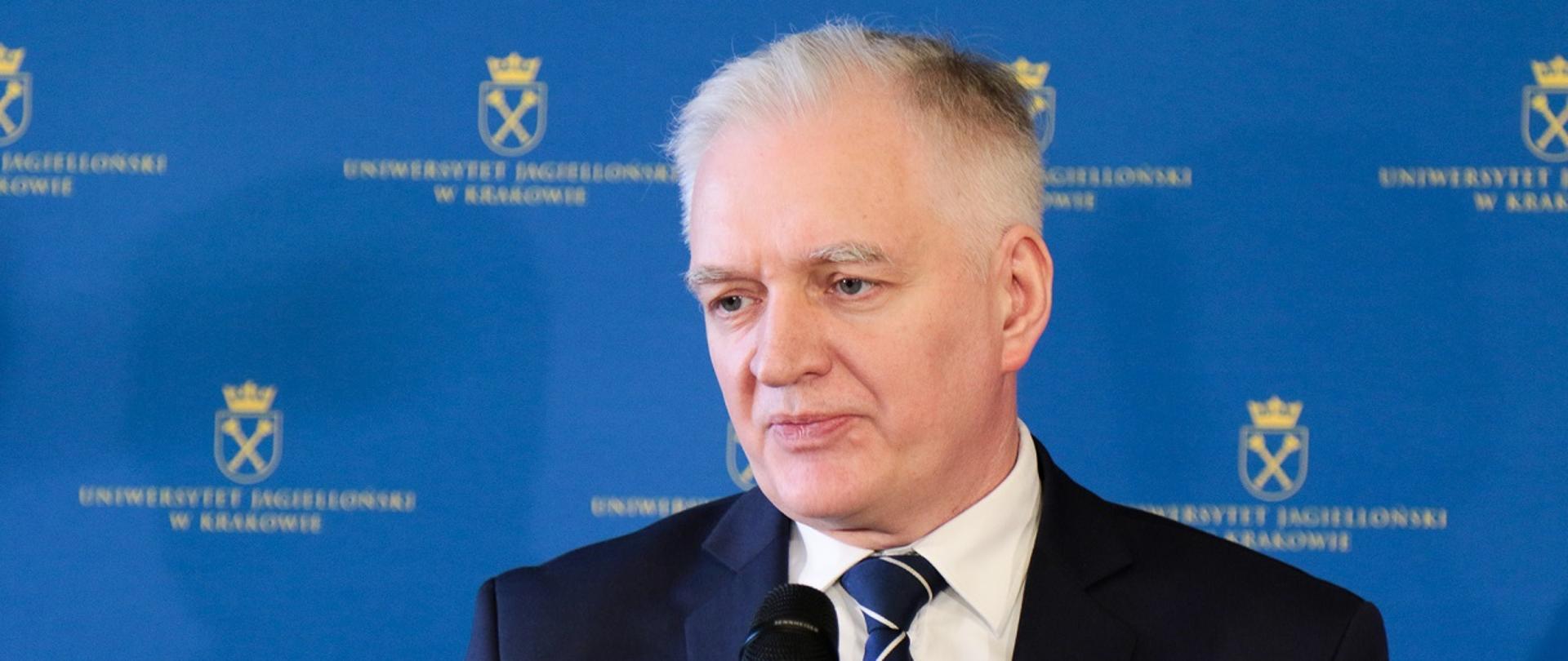 Minister Jarosław Gowin na UJ. Minister przemawia do mikrofonu, za nim niebieska ściana z żółtym logiem UJ.