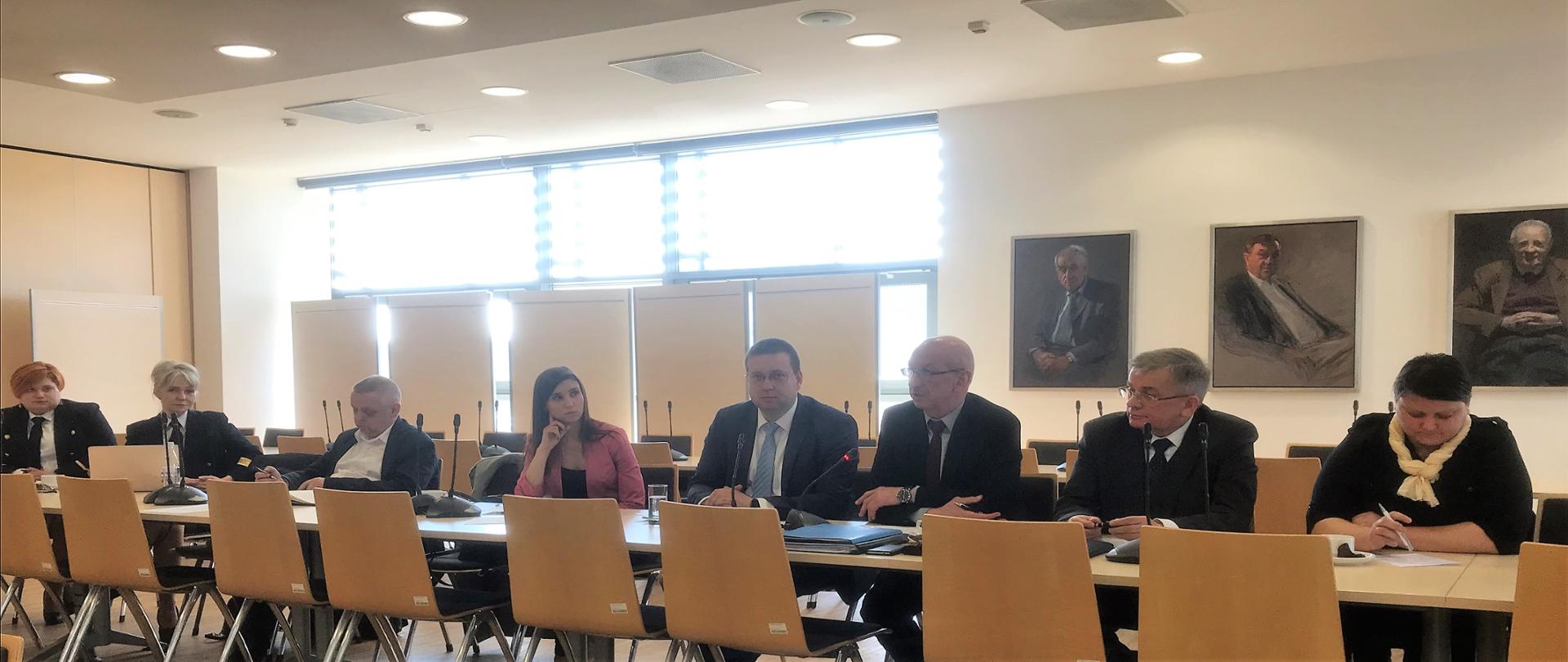 Uczestnicy konferencji siedzący przy stole i słuchający prelegenta