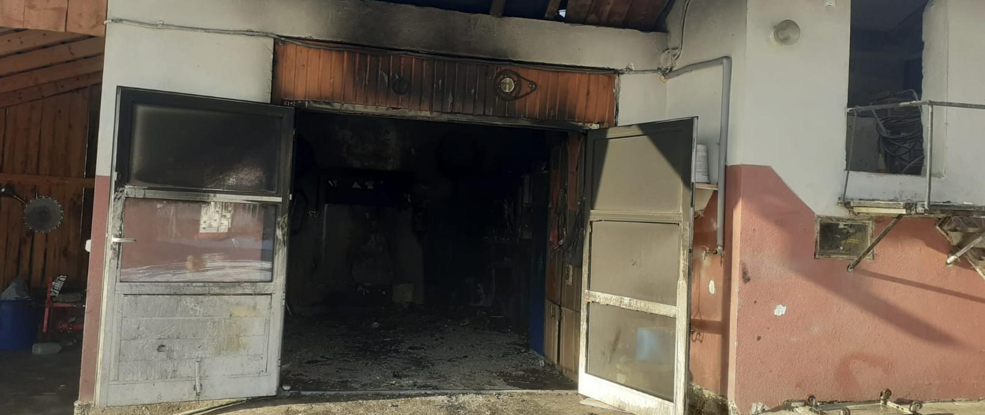 Widok otwartych drzwi do garażu w którym powstał pożar.