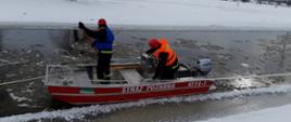 Dwóch strażaków ubranych w kapoki na łodzi prowadzących działania poszukiwawcze na rzece Nurzec.