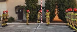 Na placu komendy powiatowej państwowej straży pożarnej w Żarach podczas zmiany służbowej strażacy z dwóch zmian uroczyście przekazują służbę z okazji 103 rocznicy odzyskania niepodległości przez Polskę. Jest wciągana flaga na maszt i odegrany hymn Polski. 