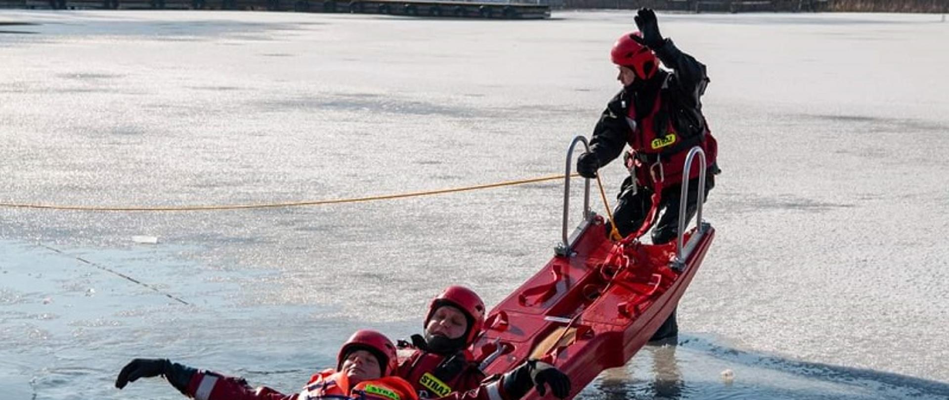 Zdjęcie przedstawia strażaków podejmujących osobę poszkodowaną z wody
