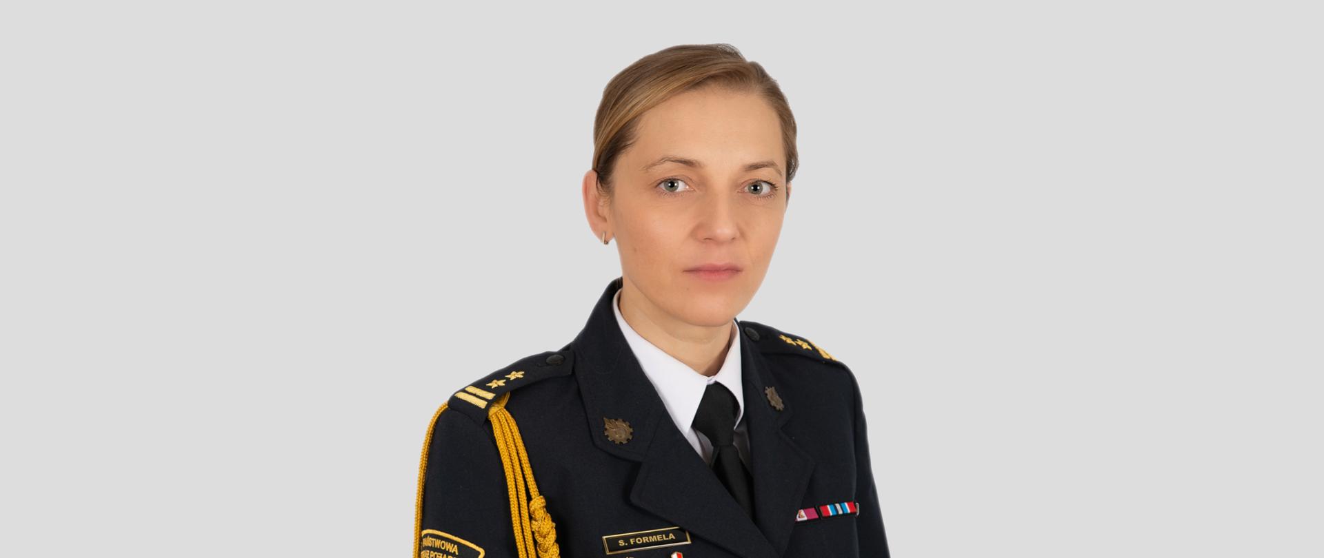 Zdjęcie Pani Komendant Powiatowej PSP w Stargardzie w mundurze galowym na jasnym tle.