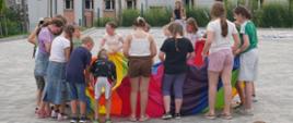 Kolorowe zdjęcie przedstawia dzieci bawiące się w trakcie festynu