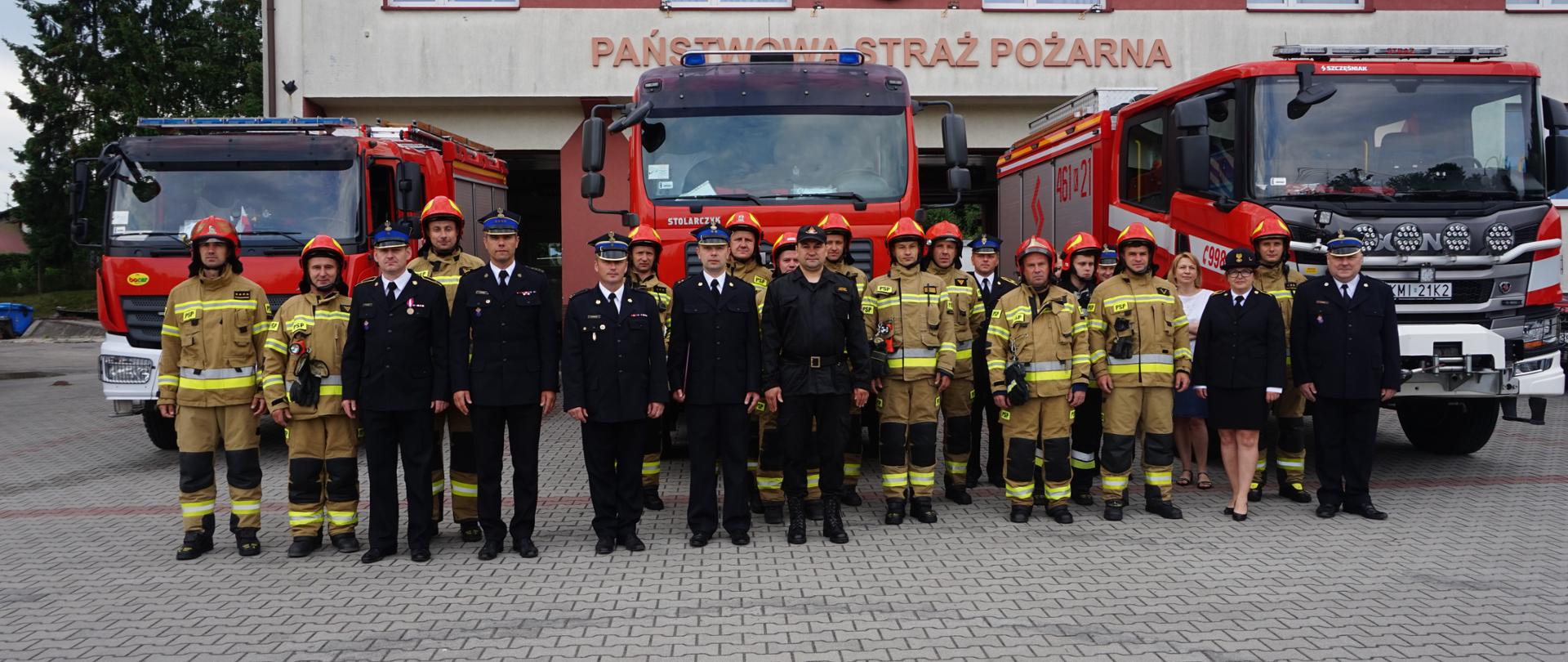 Na zdjęciu widoczni strażacy z Jednostki Ratowniczo- Gaśniczej w Miechowie na tle samochodów pożarniczych oraz budynku jednostki.
