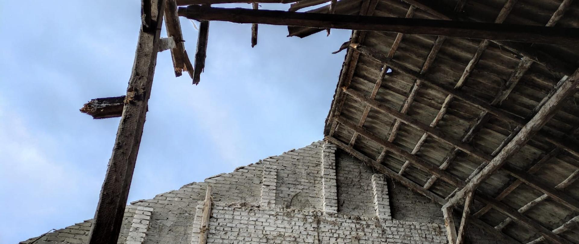 Zdjęcie przedstawia zawalony dach na budynku gospodarczym. 