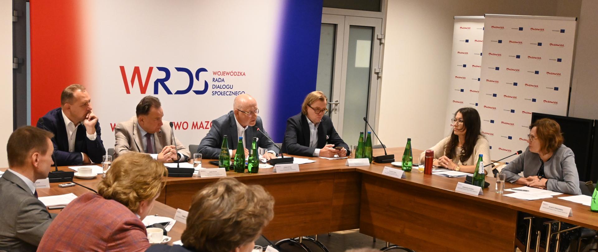 grupa osób siedzi przy stole w kształcie podkowy