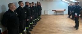 Zdjęcie przedstawia strażaków stojących w szeregu w świetlicy podczas wręczenie nagrody.