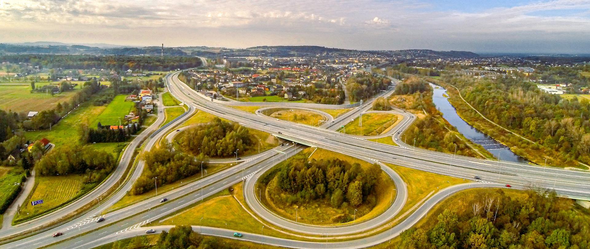 Widok w kierunku północnym na drogowy węzeł typu „koniczyna” na skrzyżowaniu drogi ekspresowej S51 i drogi krajowej nr 81. W lewej części fotografii widoczna rzeka Wisła w Skoczowie. 