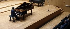 Pianista gra na fortepianie na scenie sali koncertowej PSM