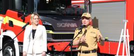 Na pierwszym planie: Minister klimatu i środowiska Pani Anna Moskwa Komendant Główny Państwowej Straży Pożarnej gen. brygadier Andrzej Bartkowiak. W tle samochody pożarnicze.
