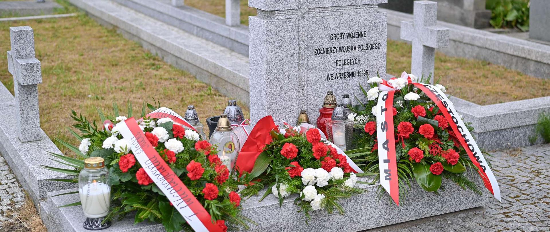 Nagrobek żołnierzy wojska polskiego poległych we wrześniu 1939 roku pod którym stoją znicze oraz wieńce z biało-czerwonych róż