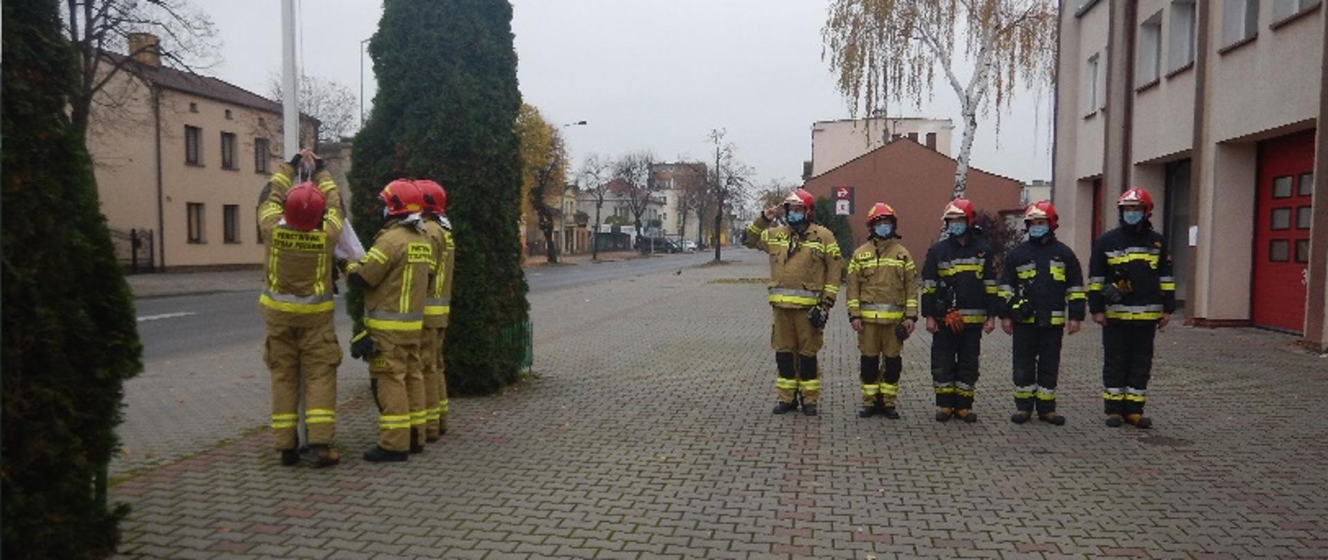 Zdjęcie przedstawia zmianę służbową, która śpiewa Mazurka Dąbrowskiego i wciąga flagę na maszt.