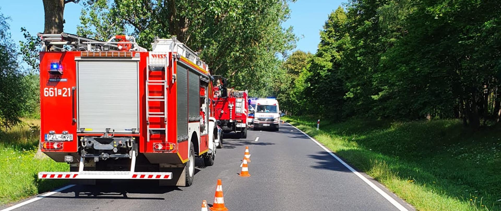 Na zdjęciu widoczne sa samochody strażackie na poboczu drogi oraz pachołki drogowe