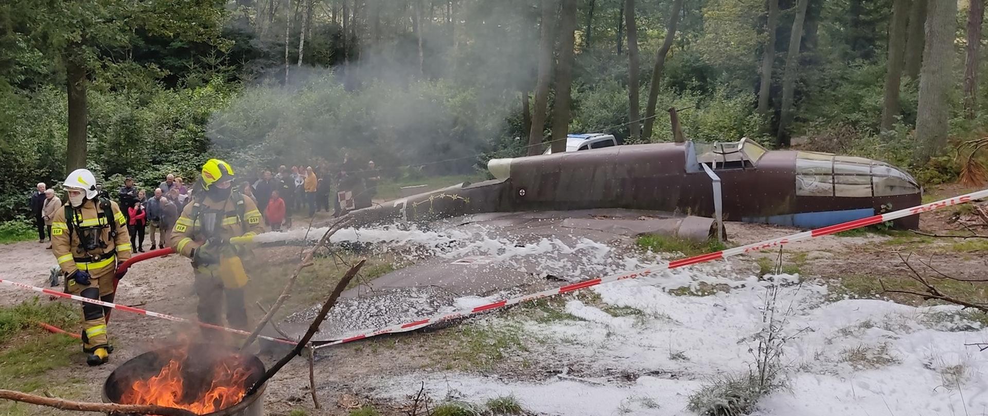 Na zdjęciu strażacy OSP Dłutów podają prąd piany ciężkiej w miejsce wypadku lotniczego. W tle grupa obserwatorów ćwiczeń.