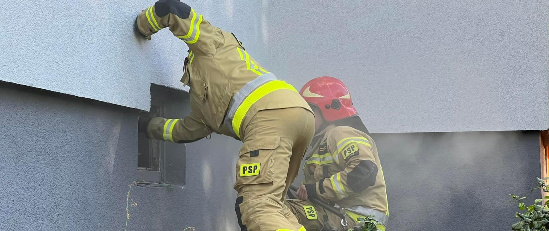 Na zdjęciu widać ratowników ze straży pożarnej. Prowadzą działania ratowniczo-gaśnicze. Umundurowani. Zdjęcie wykonane w ciągu dnia.