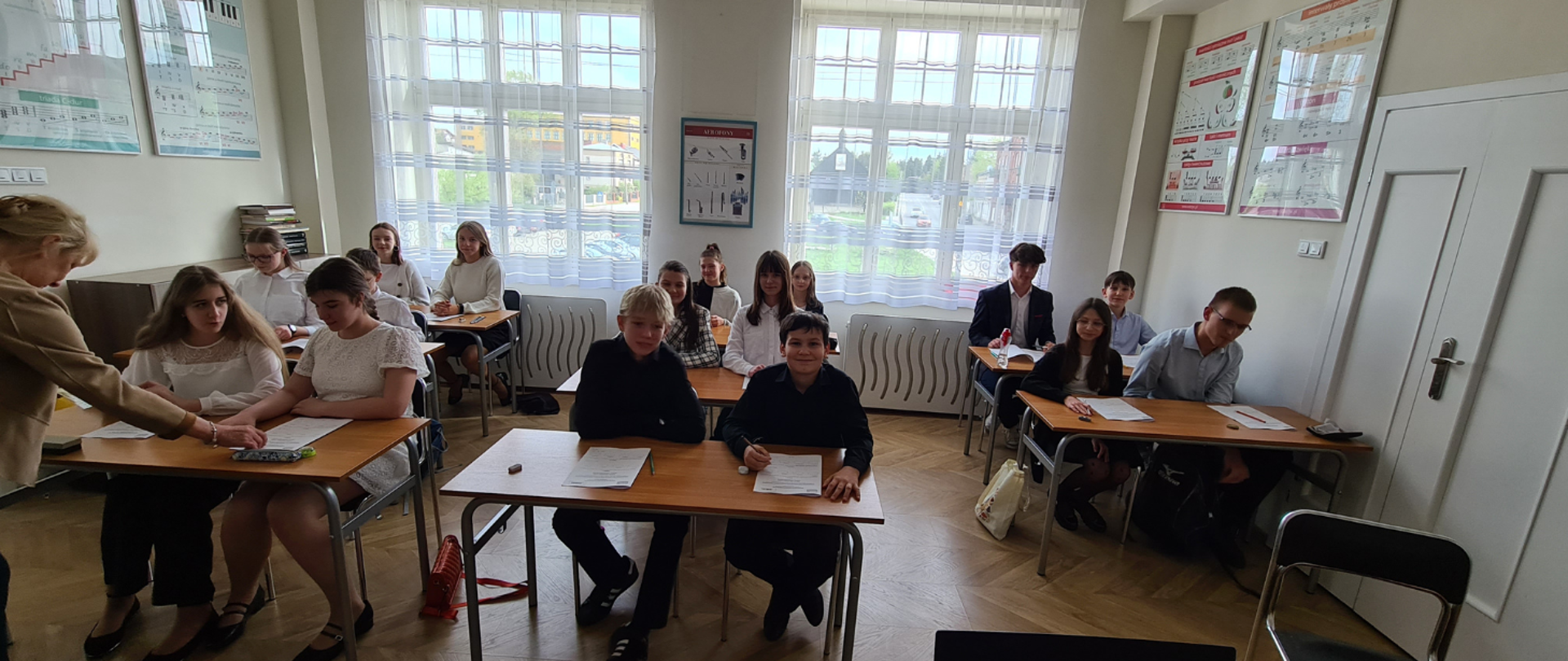 Zdjęcie uczniów ubranych w galowe stroje, którzy szykują się do pisania testu z Kształcenia słuchu i Audycji Muzycznych