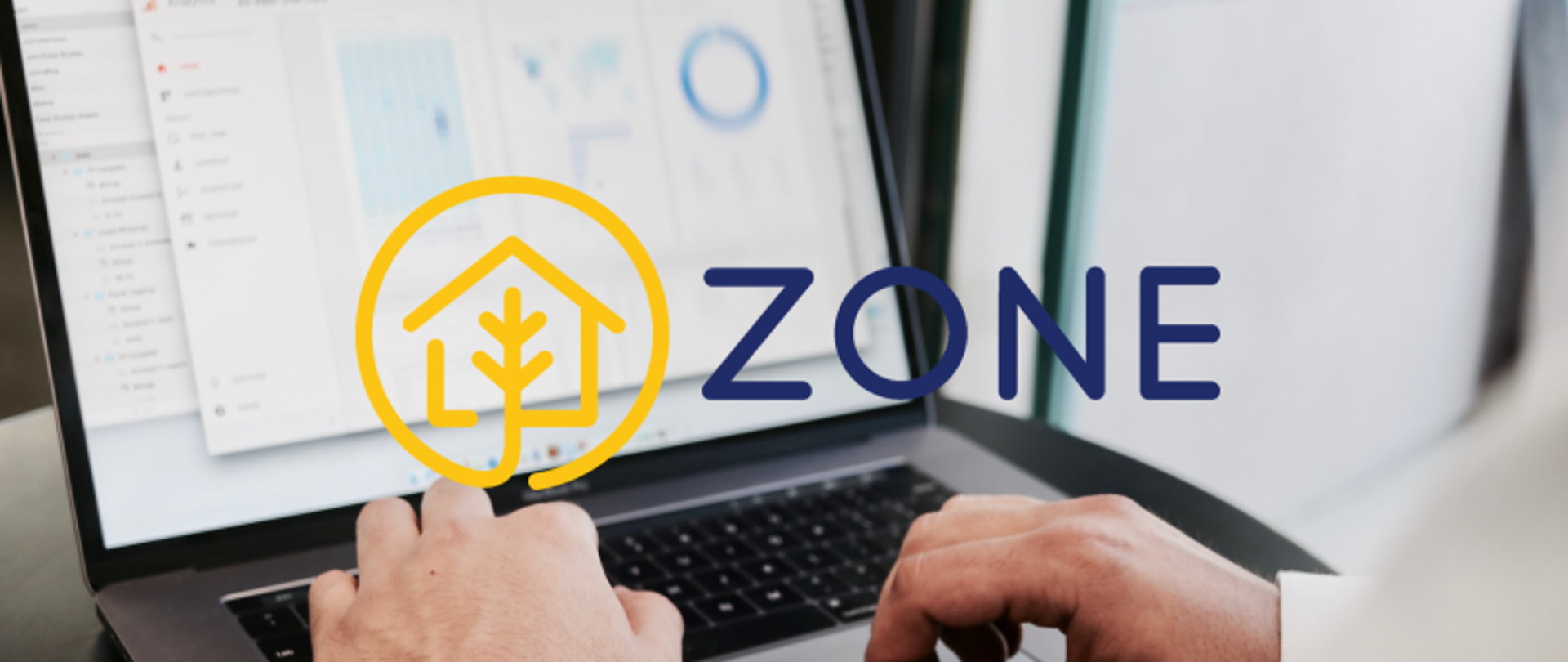 Laptop z wykresami na ekranie, użytkownik w trakcie pracy; na zdjęciu logo z domem i drzewem oraz napis „ZONE”.