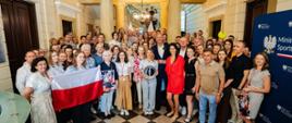 Zdjęcie zbiorowe zrobione w hallu wejściowym siedziby MSiT przedstawiające pracowników MSiT, w tym ministra Jakuba Rutnickiego, z Mają Chwalińską.