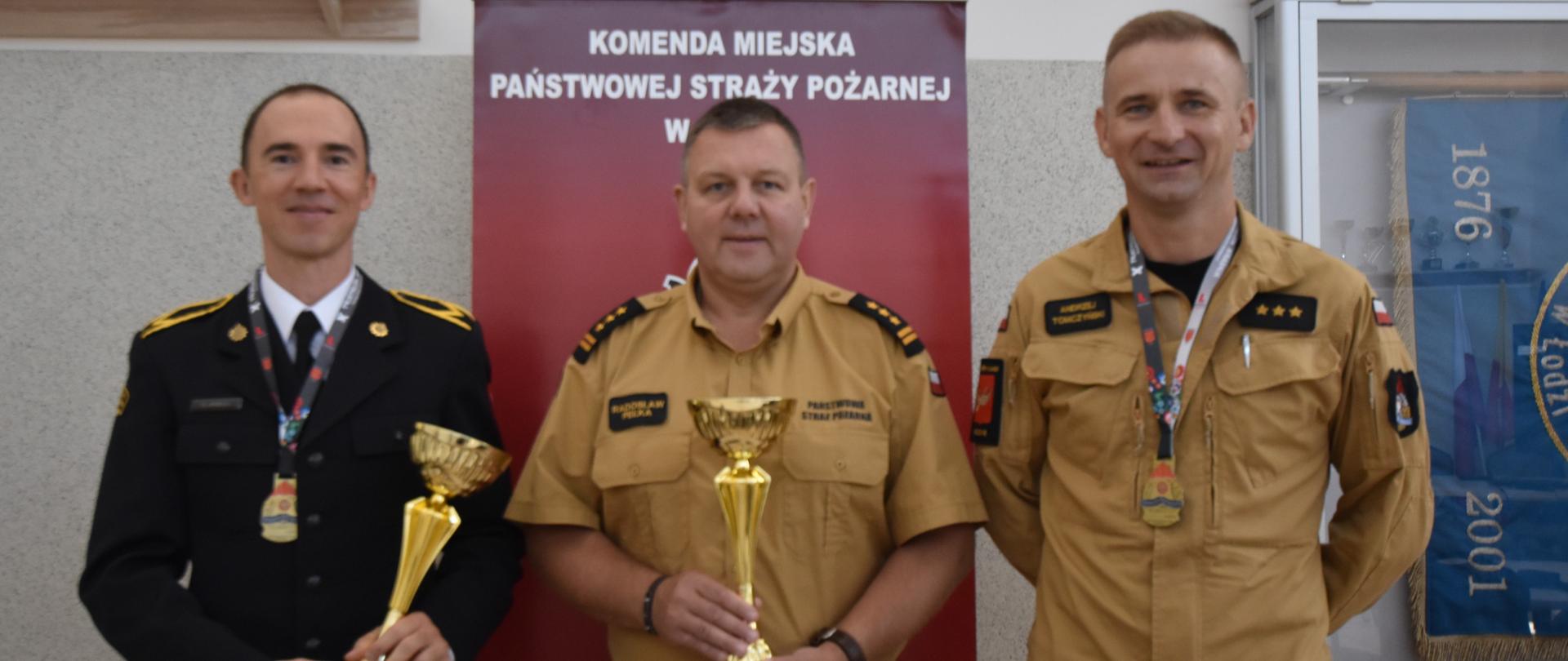 Z-ca Komendanta Miejskiego PSP w Łodzi wraz ze strażakami trzymają puchary w ręku