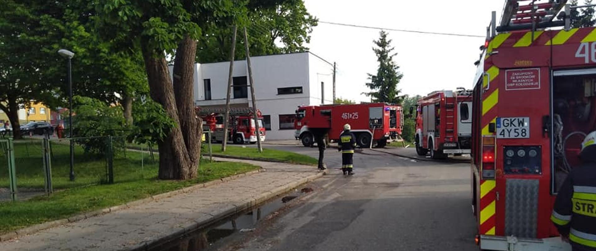 Pojazdy ratownicze stoją przy budynku, w którym rozwijał się pożar
