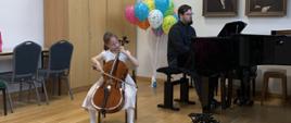 Dziewczynka gra na wiolonczeli z akompaniamentem pianisty.