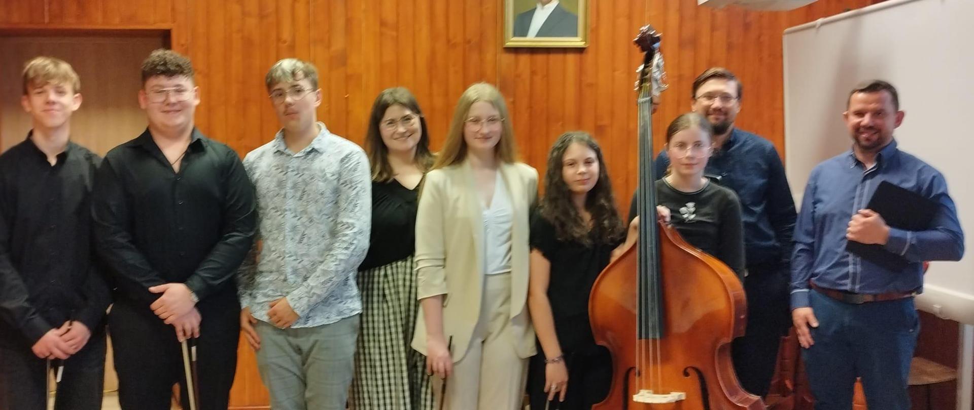 uczniowie klasy kontrabasu na zdjęciu grupowym z nauczycielką i akompaniatorami w sali kameralnej PSM Mielec podczas swojego koncertu klasowego