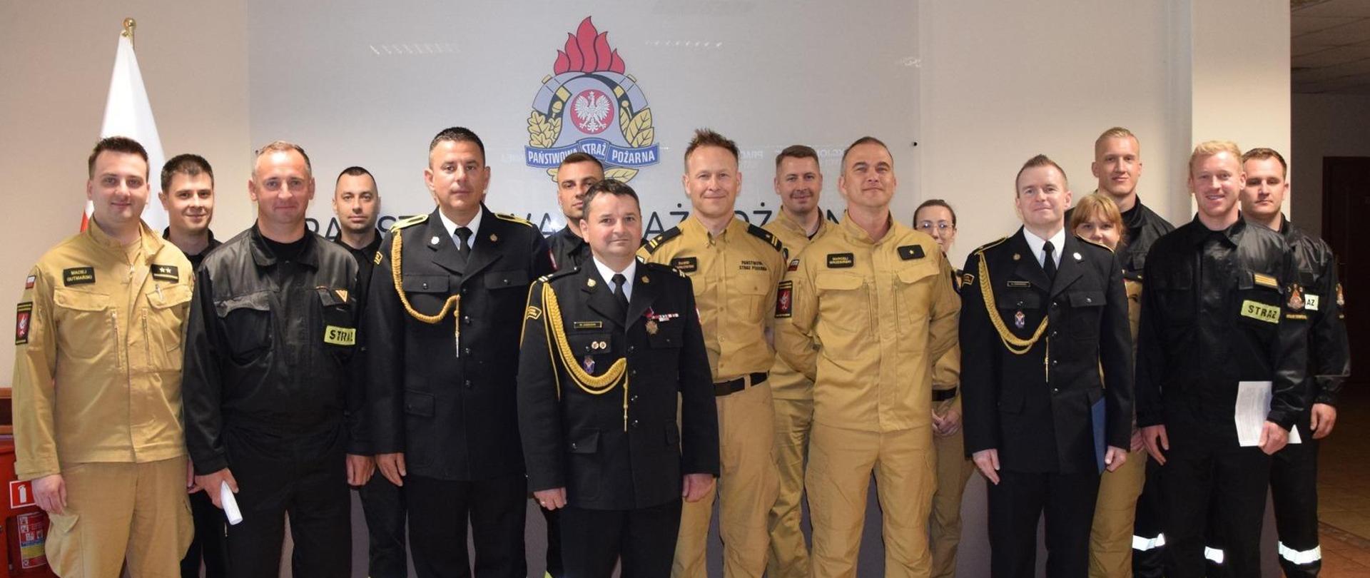 Uczestnicy uroczystej zbiórki stoją ustawieni w dwuszeregu. 