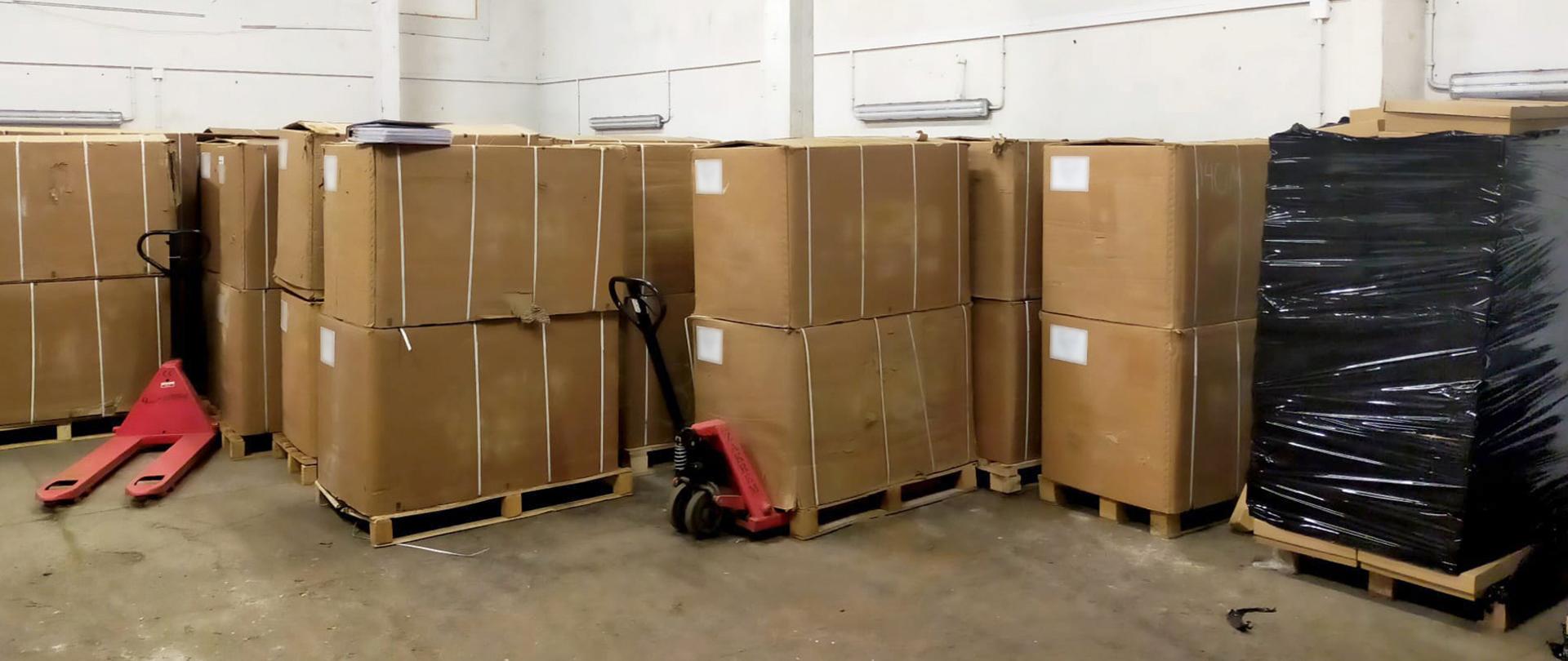 Kartony z tytoniem na paletach w magazynie.