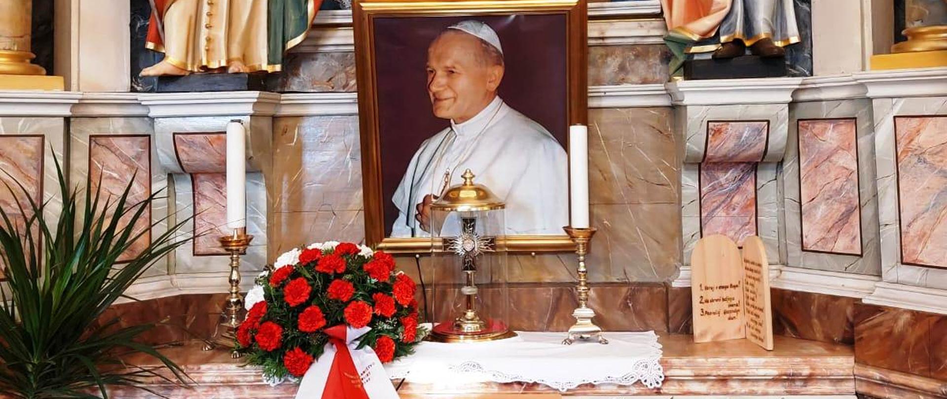 Ambasador RP w Słowenii Krzysztof Olendzki wraz z małżonką Joanną Olendzką składają biało-czerwone kwiaty przy relikwiach św. Jana Pawła II w kościele św. Mikołaja w Logatecu. 