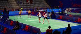 Zdjęcie przedstawia zawodników podczas meczu w badmintona w hali jaskółka