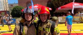 Zdjęcie przedstawia strażaków pozujących do zdjęcia ubranych w ubrania specjalne z hełmami na głowach - kadr panoramiczny