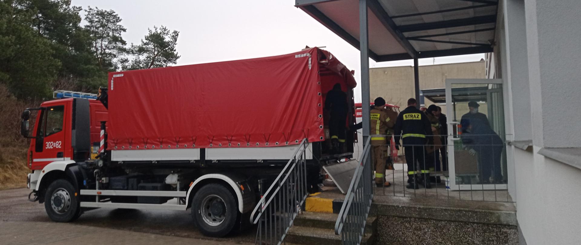 Strażacy transportują palety ze sprzętem medycznym