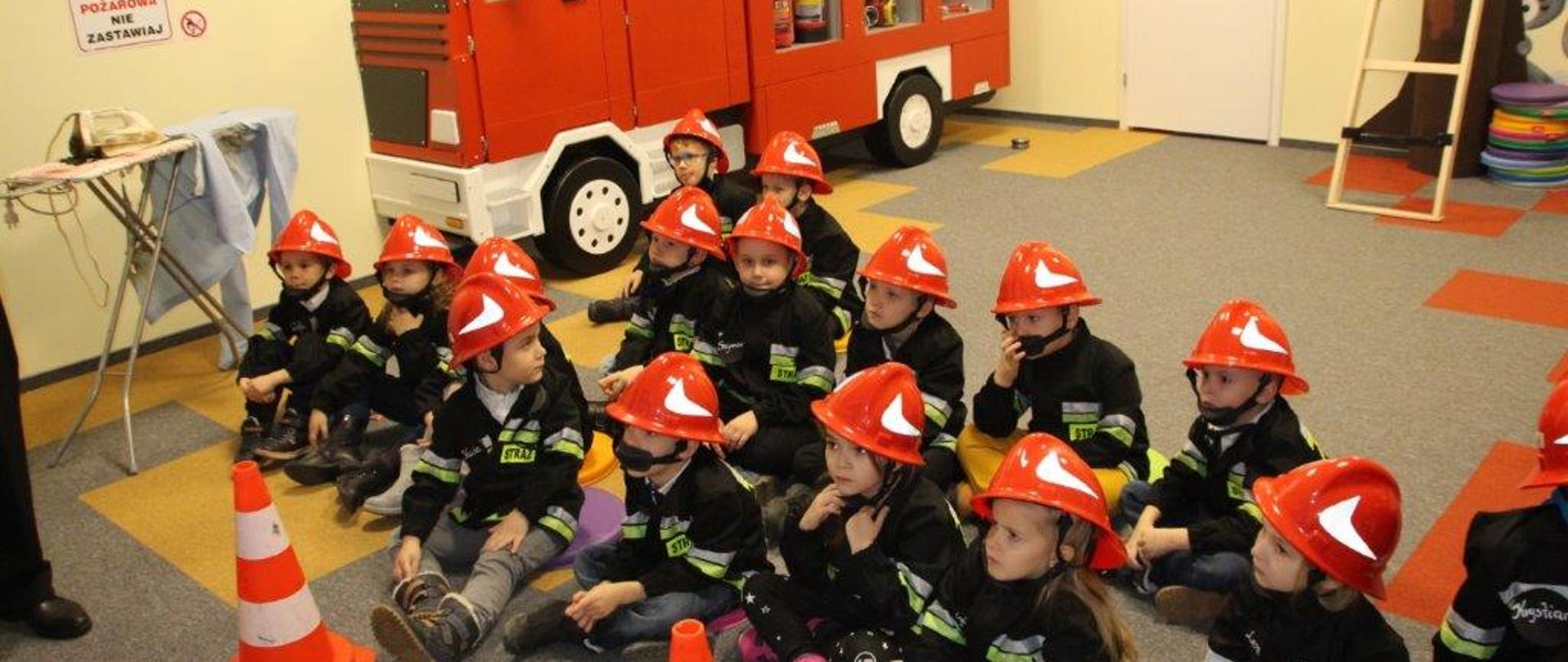 Na zdjęciu gromada dzieci w strojach strażackich podczas trwania zajęć.