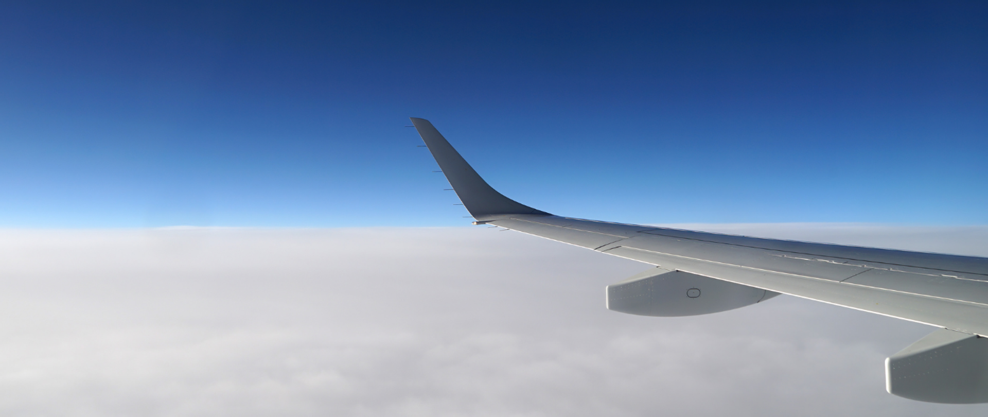 Skrzydło lecącego samolotu na tle chmur i błękitnego nieba