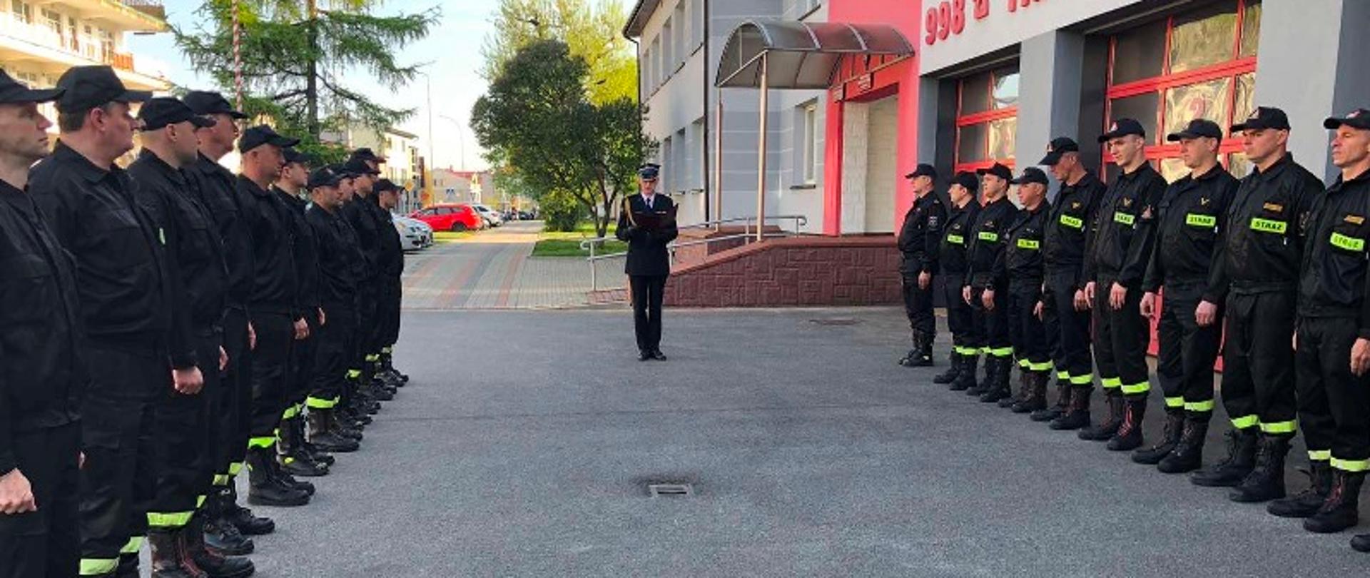 Na placu Komendy Miejskiej PSP w Tarnobrzegu , w dwóch szeregach naprzeciw siebie stoją strażacy w umundurowaniu koszarowym. Przed nimi stoi strażak w umundurowaniu wyjściowy, który odczytuje życzenia.