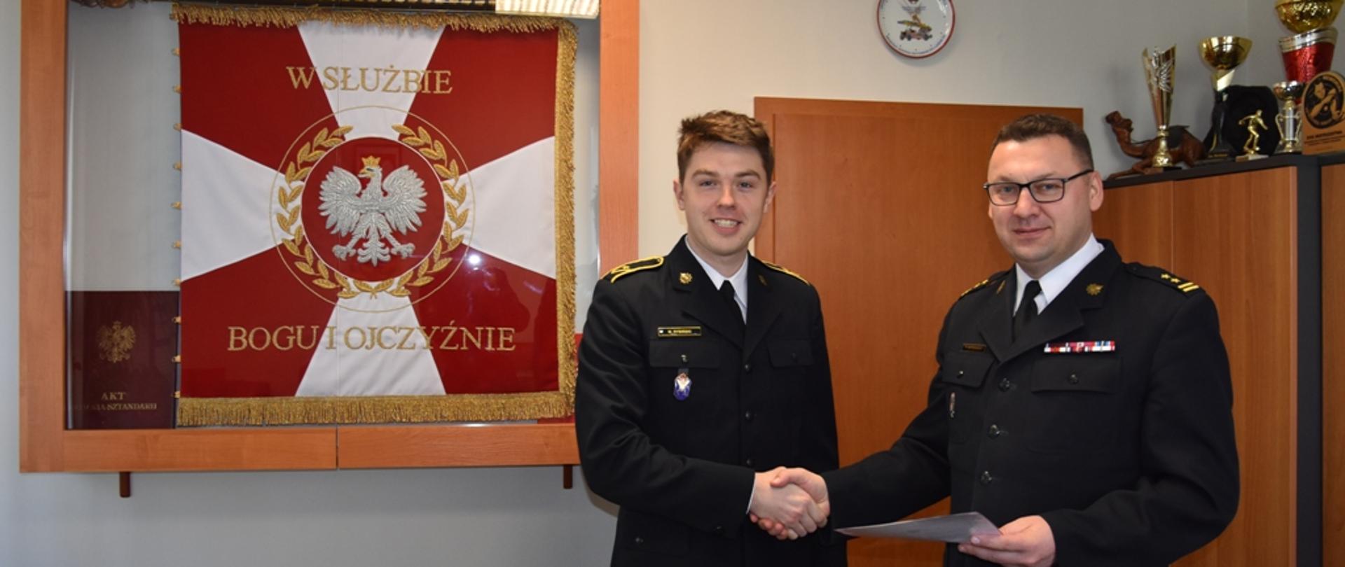 Bryg. Tomasz Ostrowski wręcza mł. asp. Marcinowi Rybińskiemu akt mianowania na stanowisko dowódcy zastępu.