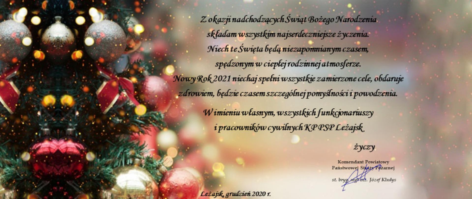 Zdjęcie przedstawia kartkę świąteczną Bożonarodzeniową na której znajdują się idąc od lewej krawędzi kartki fragment choinki ubranej w bombki, kokardki, ozdoby. Od środka ku prawej krawędzi następuje rozmycie tła na którym widać skrzące efekty świetlne. Na kartce na środku widnieją życzenia o treści: „Z okazji nadchodzących Świąt Bożego Narodzenia składam wszystkim najserdeczniejsze życzenia. Niech te Święta będą niezapomnianym czasem, spędzonym w ciepłej rodzinnej atmosferze. Nowy Rok 2021 niechaj spełni wszystkie zamierzone cele, obdaruje zdrowiem, będzie czasem szczególnej pomyślności i powodzenia. W imieniu własnym, wszystkich funkcjonariuszy i pracowników cywilnych Komendy Powiatowej Państwowej Straży Pożarnej w Leżajsku życzy” tu pod życzeniami pieczątka komendanta, starszego brygadiera mgr inż. Józefa Kludysa z własnoręcznym Podpisem. Na dole po środku widnieje napis „Leżajsk, grudzień 2021”. 