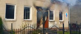 Zdjęcie przedstawia dom,który uległ spaleniu. Z wnętrzka wydobywa się dym