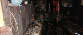 Widok spalonego pomieszczenia mieszkalnego. Całkowicie spalone wyposażenie, okopcone ściany.