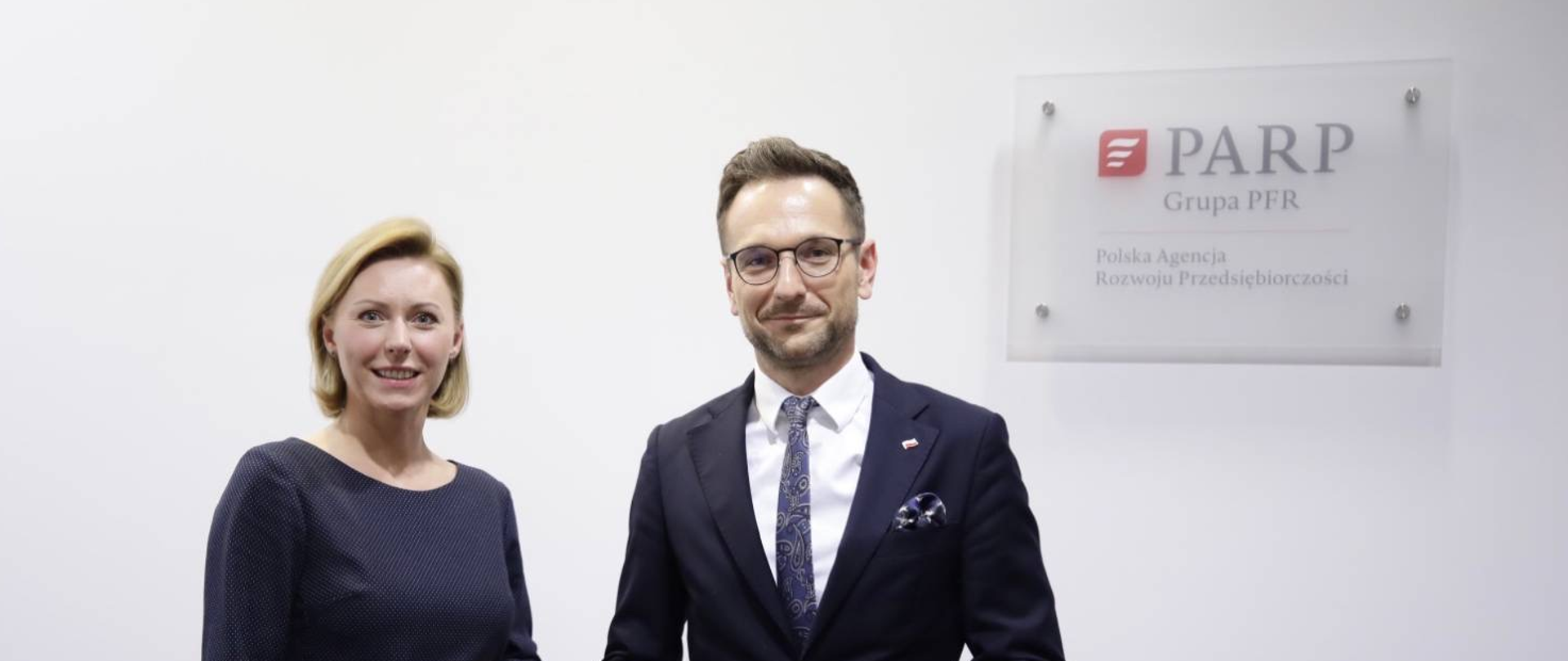 Na zdjęciu widoczne sylwetki ministra Waldemara Budy oraz prezes PARP Poznań Magdaleny Hilszer, obok logo PARP.