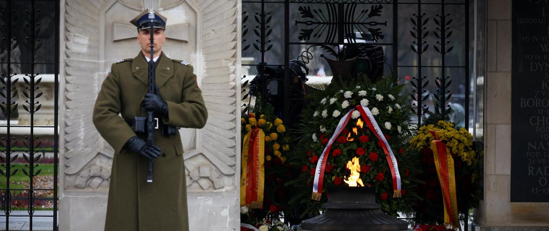 Żołnierz stoi w płaszczu z karabinem przy pomniku