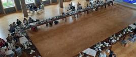 Praca w zespołach - uczestnicy spotkania dyskutują w kilkuosobowych zespołach w różnych częściach sali obrad (ujęcie z góry na salę obrad)