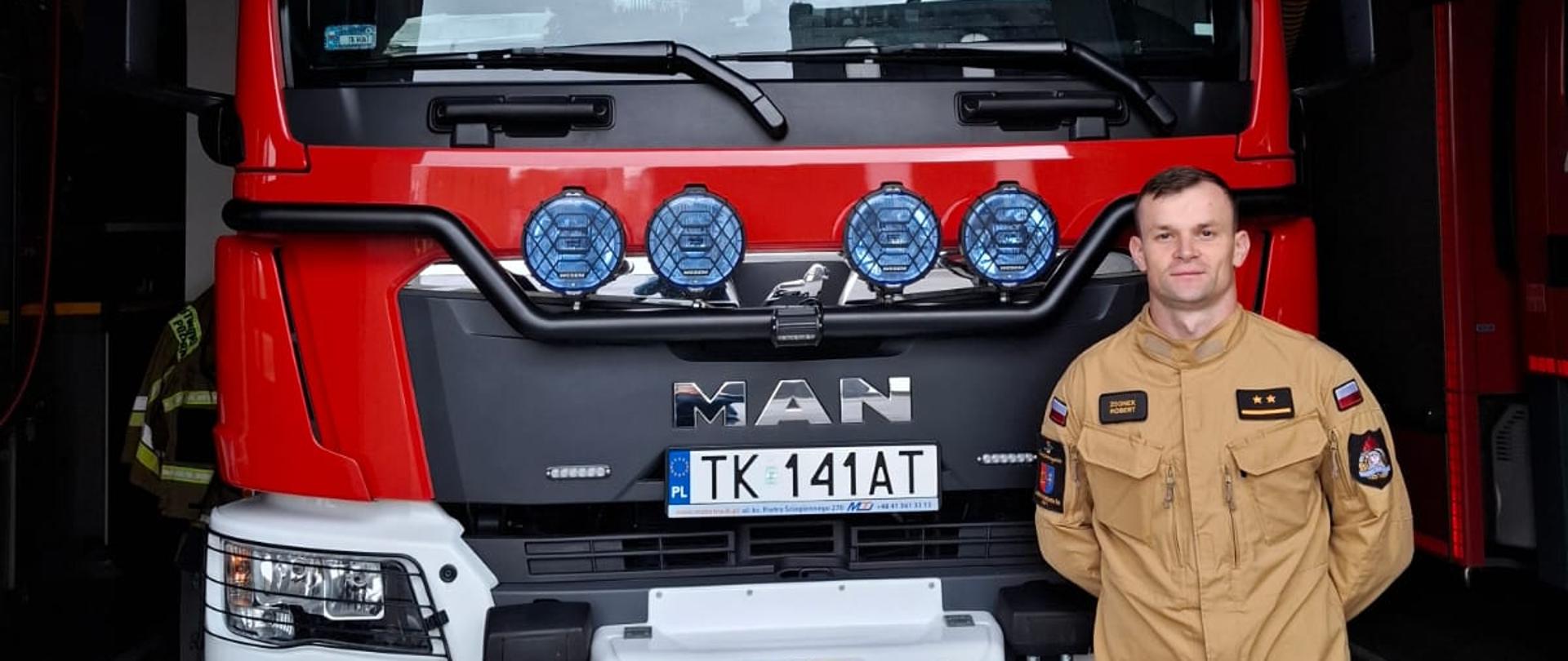 Na zdjęciu widoczny funkcjonariusz PSP na tle samochodu bojowego.